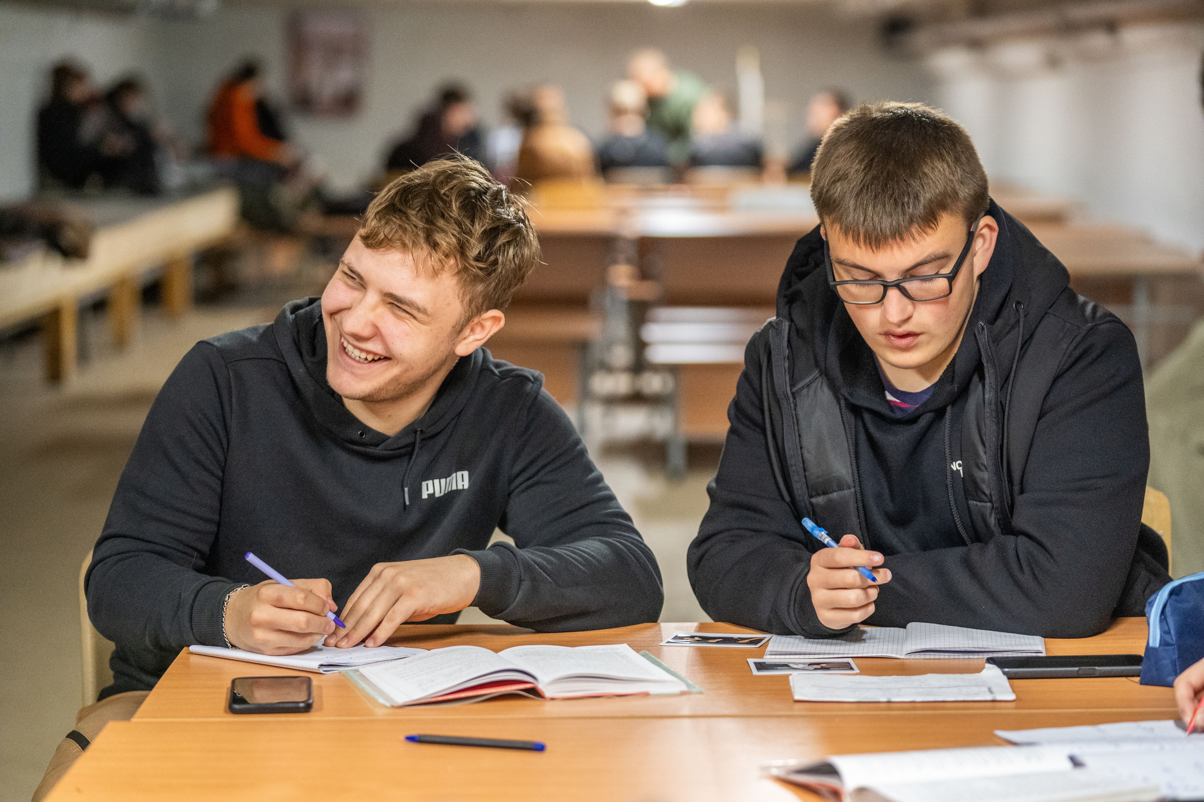 Kyrylo* and Yevhen* study in the school shelter during air alert.