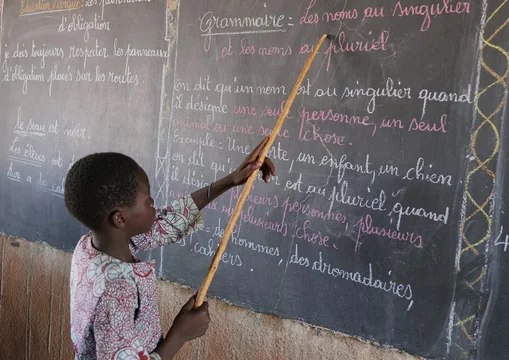 CH1545245-Souleymane-aged-14-points-to-words-on-a-blackboard-at-school-Yatenga-province-Burkina-Faso