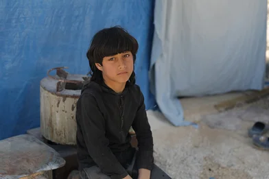 De achtjarige Mamdouh zit voor een tent waar hij met zijn familie leeft na de aardbeving in Turkije en Syrië