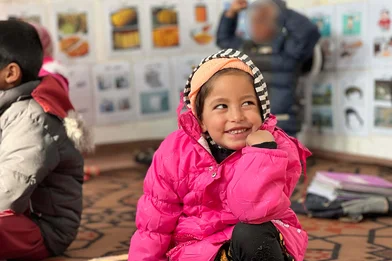 Kind 4 jaar in knalroze witerjaszit op de grond in een klas voor dove kinderen in Kabul Kind 4 jaar in knalroze witerjaszit op de grond in een klas voor dove kinderen in Kabul
