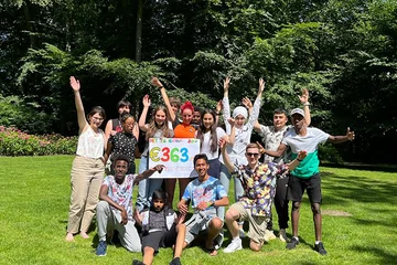 Groep adolecenten juigen, houden bord vast met tekst: €363,-